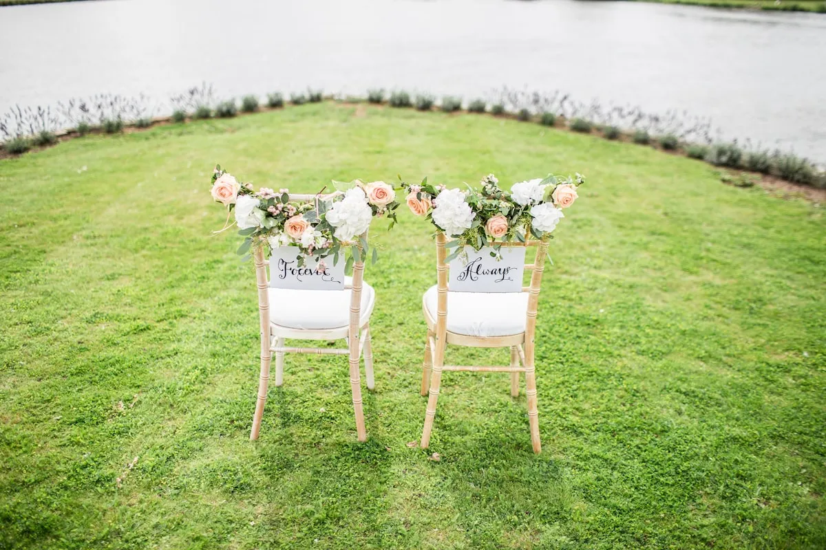 Duas cadeiras decoradas com flores, reservadas para os noivos